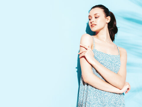 Young beautiful smiling female in trendy summer dress. Sexy carefree woman posing near blue wall in studio. Positive brunette model having fun.Cheerful and happy. Isolated