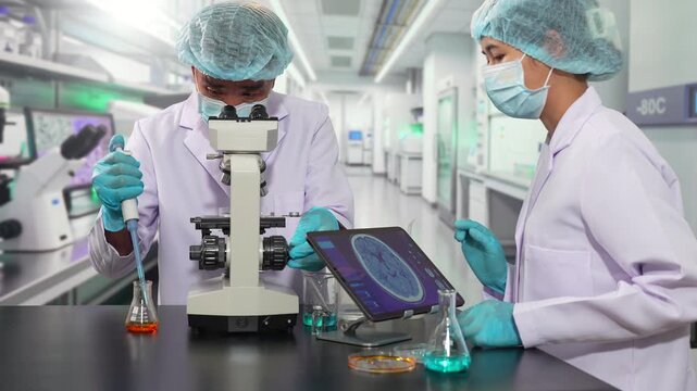 researchers analyzing cell culture in petri dish near laboratory bottle at workplace, biotechnology concept.