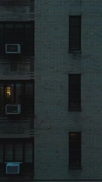 Vertical video: Slider of tiled building facade with windows. Revealing street with cars and tall buildings in background. New York City, USA
