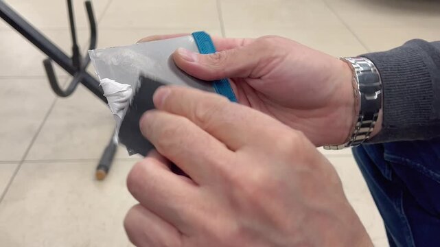 Professional auto mechanic man hands mixing two component polyester car body filler putty with a steel spatula knife tool. Professional vehicle bodywork repair, scratch, dent restoration. 