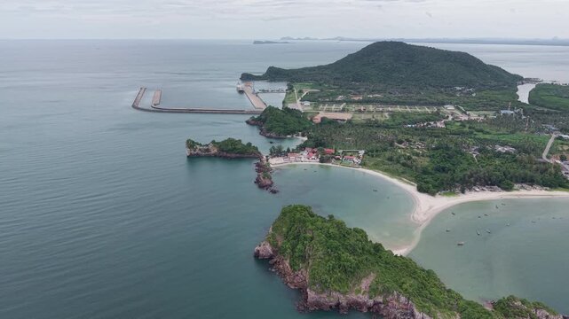 Breathtaking aerial perspective flying over a serene tropical bay featuring rocky headlands coastal temple and distant harbor in Bang Saphan, Prachuap Khiri Khan, Thailand