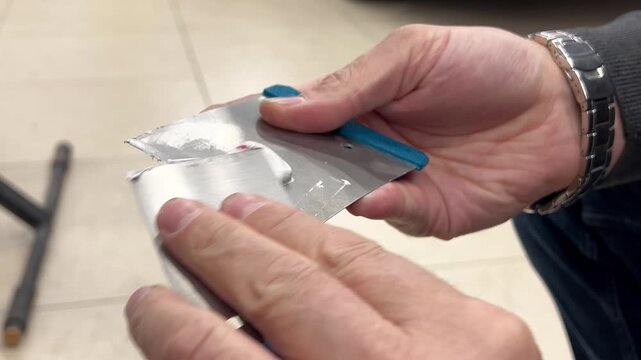 Professional auto mechanic man hands mixing two component polyester car body filler putty with a steel spatula knife tool. Professional vehicle bodywork repair, scratch, dent restoration. 