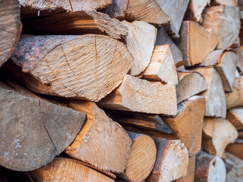 Stacked and stored split beech firewood showing cut ends and natural wood texture. Chopped hardwood prepared and stored as fuel for stove, fireplace and home heating.