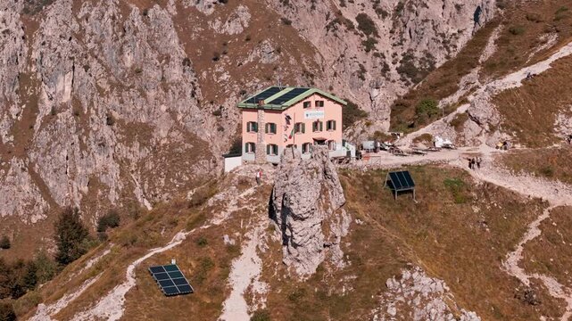 Stunning aerial footage flying away from the rosalba mountain hut, nestled on a rocky ridge in the grigna, italian alps, powered by solar panels