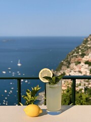 Fototapeta premium Refreshing Lemonade with Mint and Lemon Slice Overlooking a Coastal Town and Ocean View