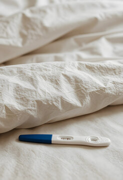 Pregnancy test with positive result, family planning and fertility concept, woman waiting for news on bed with soft morning light in bedroom interior