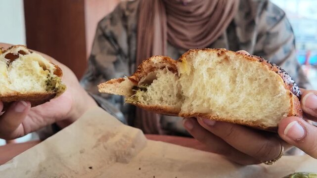 Woman Breaking Open a Fresh Poppy Seed Bread Roll
