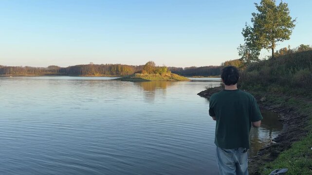 Man fishing on a quiet shore beneath a clear autumn sky, concept background