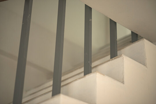 Concrete staircase steps with vertical metal railing in a modern indoor space