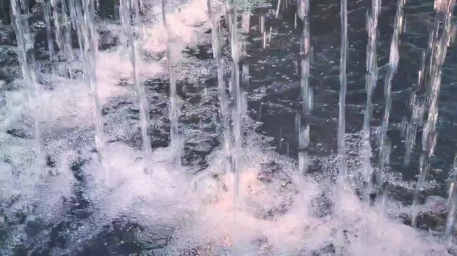 Macro shot of heavy water jets pounding outdoor stone pool generating dense white frothy bubbles and turbulent splashback
