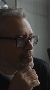 Vertical video of middle aged Caucasian businessman in eyeglasses thinking thoughtfully in office. Perfect for corporate leadership, executive decision making, and consulting projects