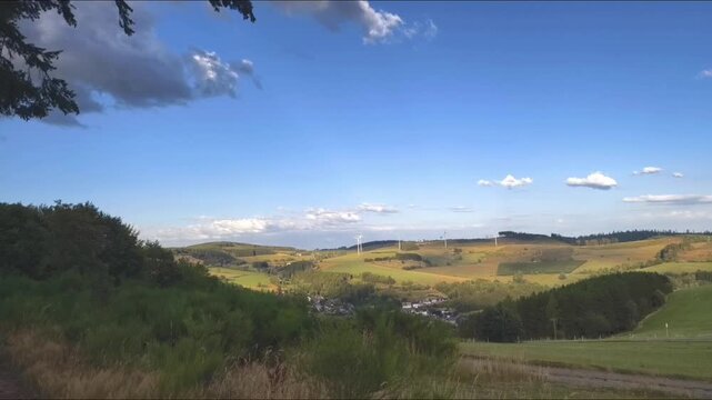 Panorama der Landschaft bei Wunderthausen (Bad Berleburg) Deutschland mit Ginster im Vordergrund, gr&uuml;nen H&uuml;geln, W&auml;ldern unter blauem Sommerhimmel im Wittgensteiner Land.
