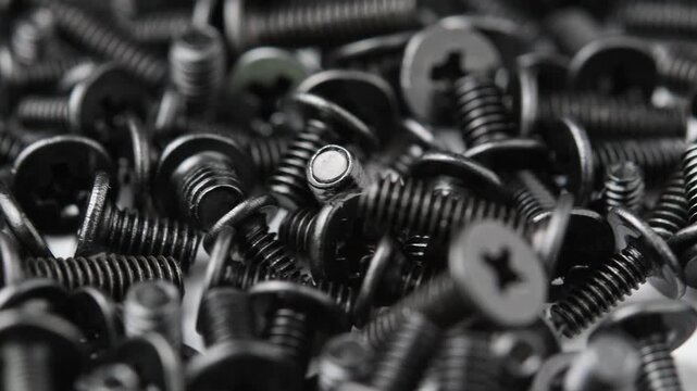 Macro view shows black screws rotating for electronics, computer repair and precision assembly.