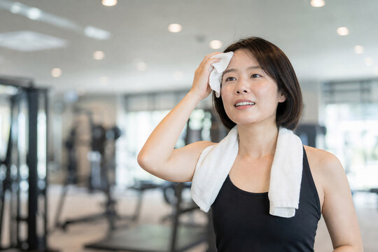 ジムで運動後にタオルで汗を拭く日本人女性