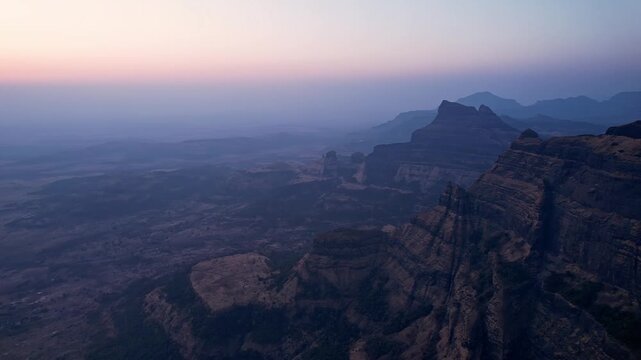 Stunning aerial view looking down a massive rocky cliff into deep valleys
