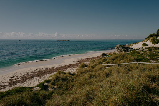 Ocean coastline with grassy dunes, sandy beach, distant boats, c