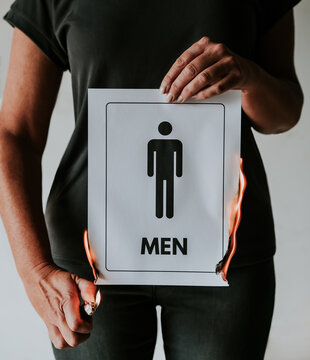 Woman burning a paper sign with a male restroom symbol