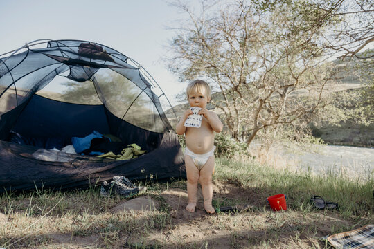 Cute toddler boy eating a snack at a campsite
