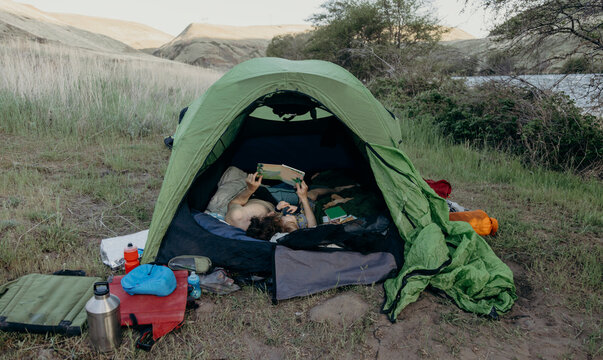 Couple reads a book together while camping outdoors