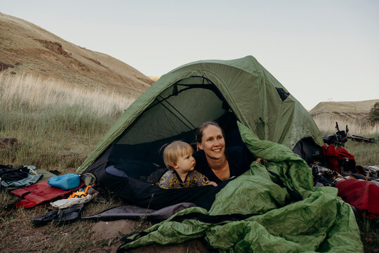 Mother and her young child look out from a tent