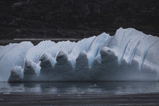 Sculpted iceberg drifts in calm cold ocean water