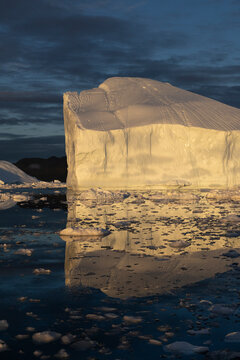 Majestic iceberg reflected in calm ocean at dusk