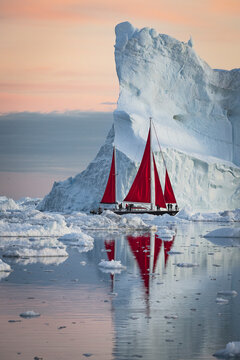 Dramatic red sailboat navigates icy polar waters
