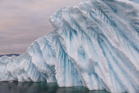 Massive grooved iceberg with blue ice floating in arctic water