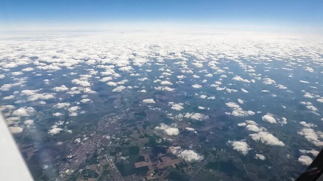 Aerial view of farmland and a town beneath scattered clouds
