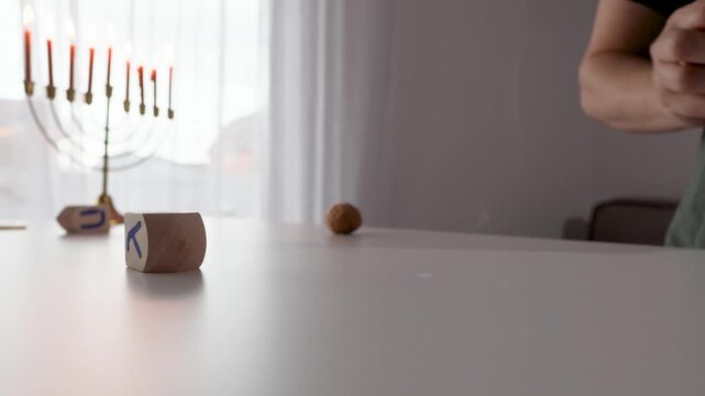 Close-up of a wooden dreidel on a table during Hanukkah with warm menorah glow