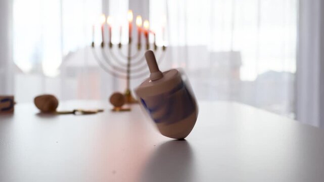 Close-up of wooden Hebrew letter blocks on Hanukkah table with lit menorah in background