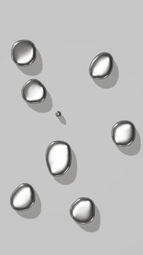 Liquid metal droplets fall, splash, spread, retract and settle on a neutral gray surface, showing metallic sheen and fluid motion