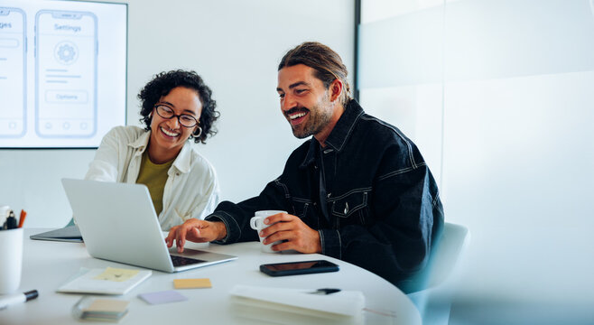 Two ux designers share a laugh over laptop