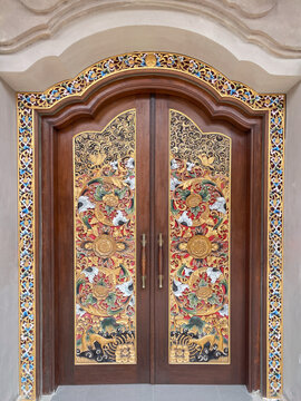 Ornate traditional church door in Bali, Indonesia, featuring intricate decorative carvings and colorful cultural architectural details.