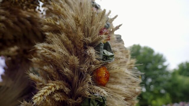 Close up of a traditional harvest wreath decorated with wheat, dried plants and colorful natural ornaments