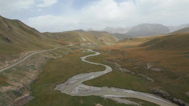 Stunning aerial perspective flying over a beautiful winding river meandering through the Kok Kiya Valley in Kyrgyzstan's vast grasslands