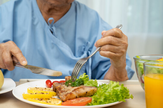 Asian elderly old lady woman patient eating Salmon steak breakfast with vegetable healthy food.