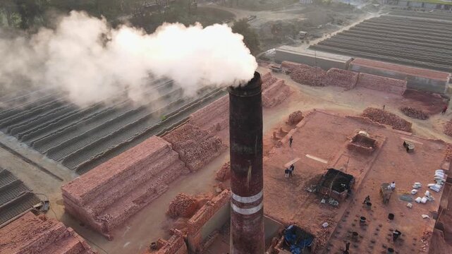Brick kiln smokestack, brick stacks and drying rows of bricks. Environment pollution concept. Drone aerial rotation shot