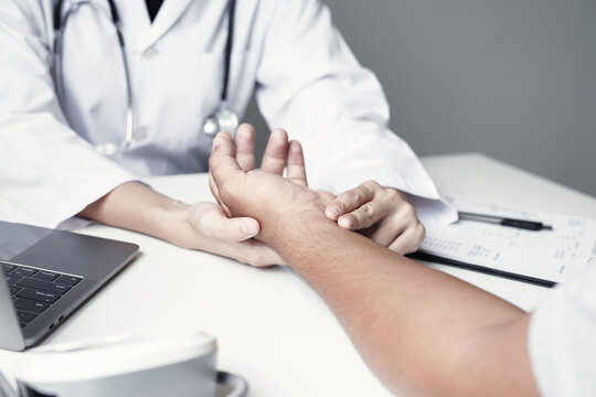 Doctor examines patient's wrist and hand during medical consultation, checking pain symptoms and joint health for diagnosis, treatment, and healthcare assessment