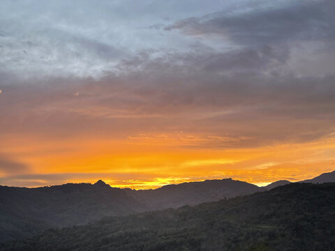 Golden sunset over a mountain landscape with dramatic clouds, creating a peaceful scenic nature background and breathtaking outdoor view.