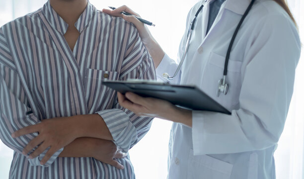 Doctor consulting patient about health condition while reviewing medical records, discussing symptoms, diagnosis, treatment, examination, care, and recovery planning
