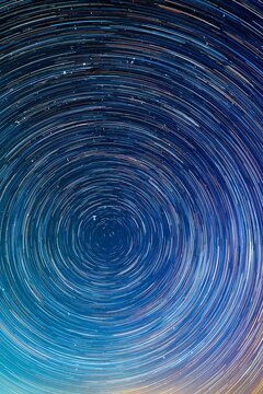 長時間露光によって美しい同心円を描く星の軌跡とグラデーションが幻想的な夜空の天体風景
