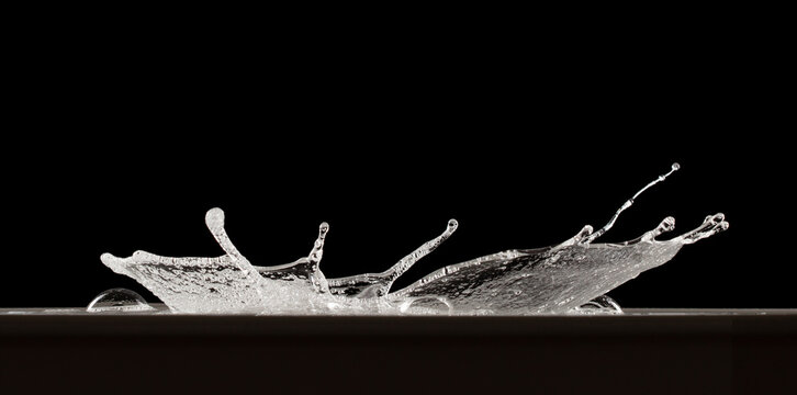 Clear transparent Gel fall in droplet line up crown. Bright translucent liquid water pouring over black background isolated. Paint liquid Gel water crown water sticky spike, Photograph