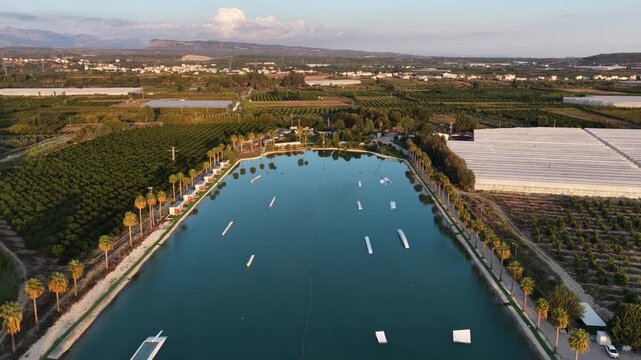 World class wakepark in Antalya, Turkey, with riders on crystal clear lakes surrounded by palm trees and mountains and multiple water obstacles for wakeboarding. Cable Wake park in Turkey.