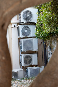 Multiple outdoor air conditioner units installed on a building facade, illustrating extreme heat, rising cooling demand, urban climate adaptation and energy consumption
