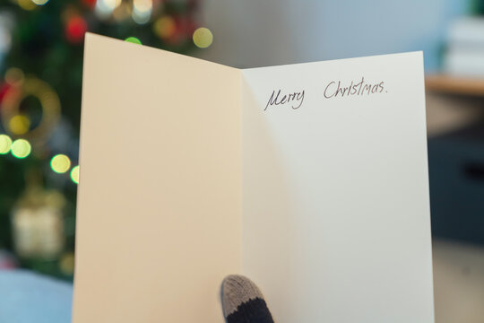 woman hand holding a Christmas greeting card, holiday celebration, festive season.