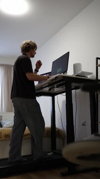 Vertical screen young man spends a typical remote workday editing video at his home computer combining routine tasks with a flexible work from home lifestyle