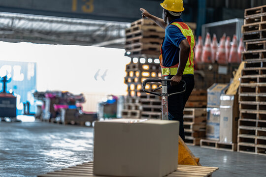 A warehouse worker moves an outbound parcel towards the dispatch door on the wet concrete floor of a distribution warehouse during a routine inventory check as part of the daily supply