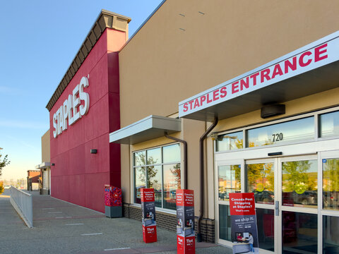 Calgary, AB, Canada. Oct 1, 2026. Exterior entrance facade and storefront signage of a Staples retail store on a sunny day.