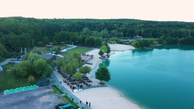 The lake is located in an abandoned quarry with blue water. Scenic aerial view of an abandoned quarry with clear blue water transformed into a public beach and recreational park with swimmers.